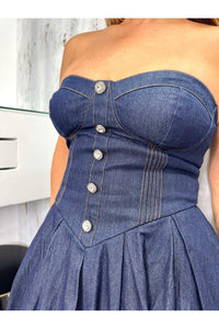 A denim midi dress featuring strapless sweetheart neckline, bustier bodice with button detail, basque waist, full skirt and back zipper closure