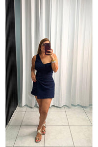 Denim skort romper featuring one shoulder neckline, front twist bottom and back zipper closure